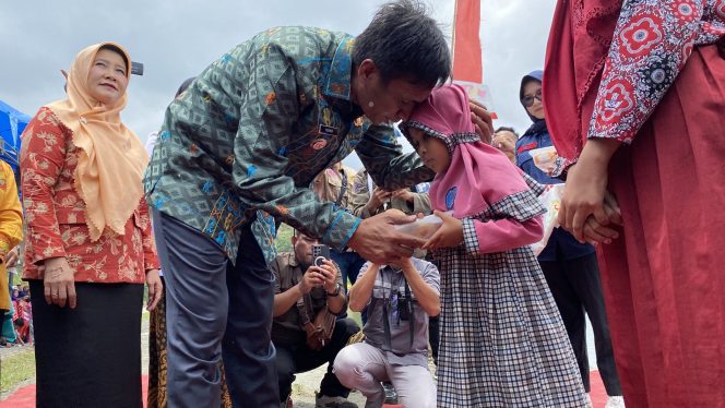 
Pj Bupati Kolaka Utara Yusmin menyerahkan makanan kepada salah seorang siswa dalam peluncuran program Makan Siang Bergizi Gratis. 